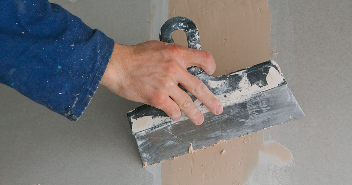 Verputzarbeiten mit dem Auftragen von Spachtelmasse auf eine Wand.